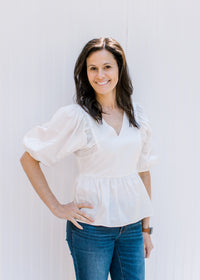 Model wearing a white babydoll top with a v-neck and bubble short sleeves. 