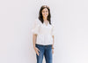 Model wearing an elegant white babydoll top with a v-neck and bubble short sleeves