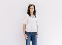 Model wearing an elegant white babydoll top with a v-neck and bubble short sleeves