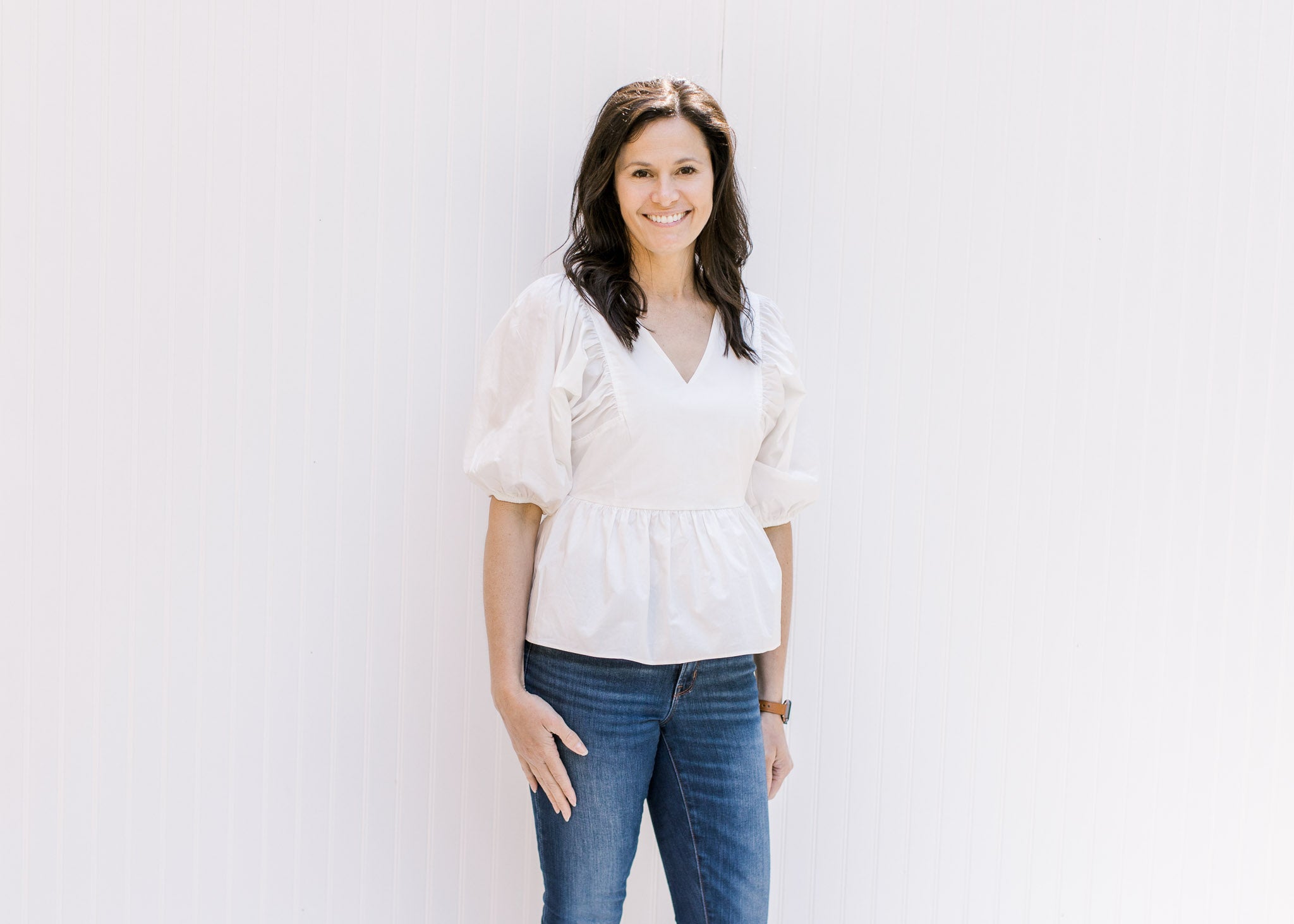 Model wearing an elegant white babydoll top with a v-neck and bubble short sleeves