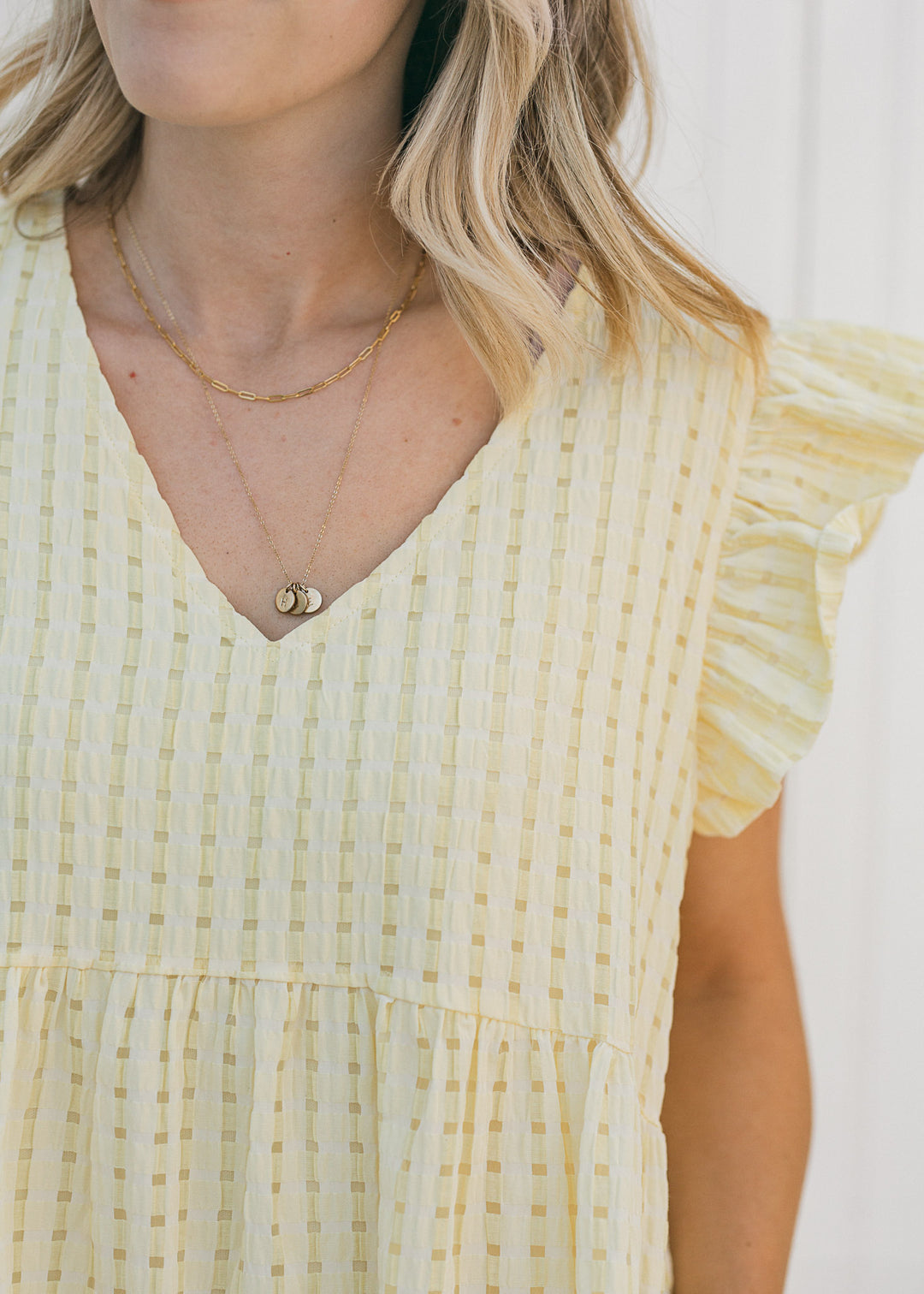 Close up of model wearing a yellow tone on tone checked dress with capped short sleeves.