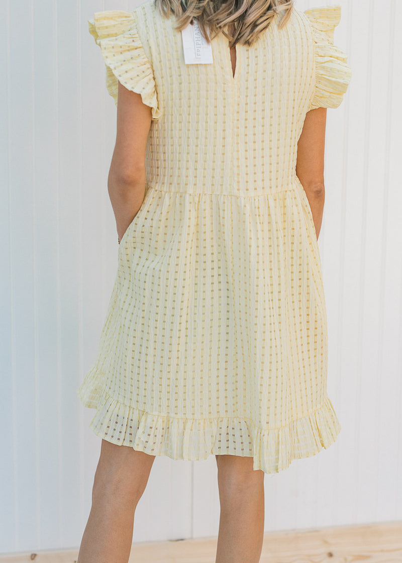 Back view of model wearing a yellow short sleeve, checkered dress with ruffle capped sleeves. 