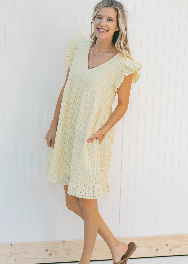 Model wearing a yellow short sleeve, checkered dress with ruffle capped sleeves and sandals. 