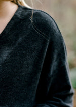 Close up of Blonde model wearing black V-neck sweater.