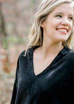 Blonde model wearing black V-neck sweater and smiling. 
