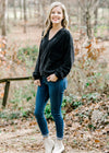 Blonde model wearing black V-neck sweater with jeans. 