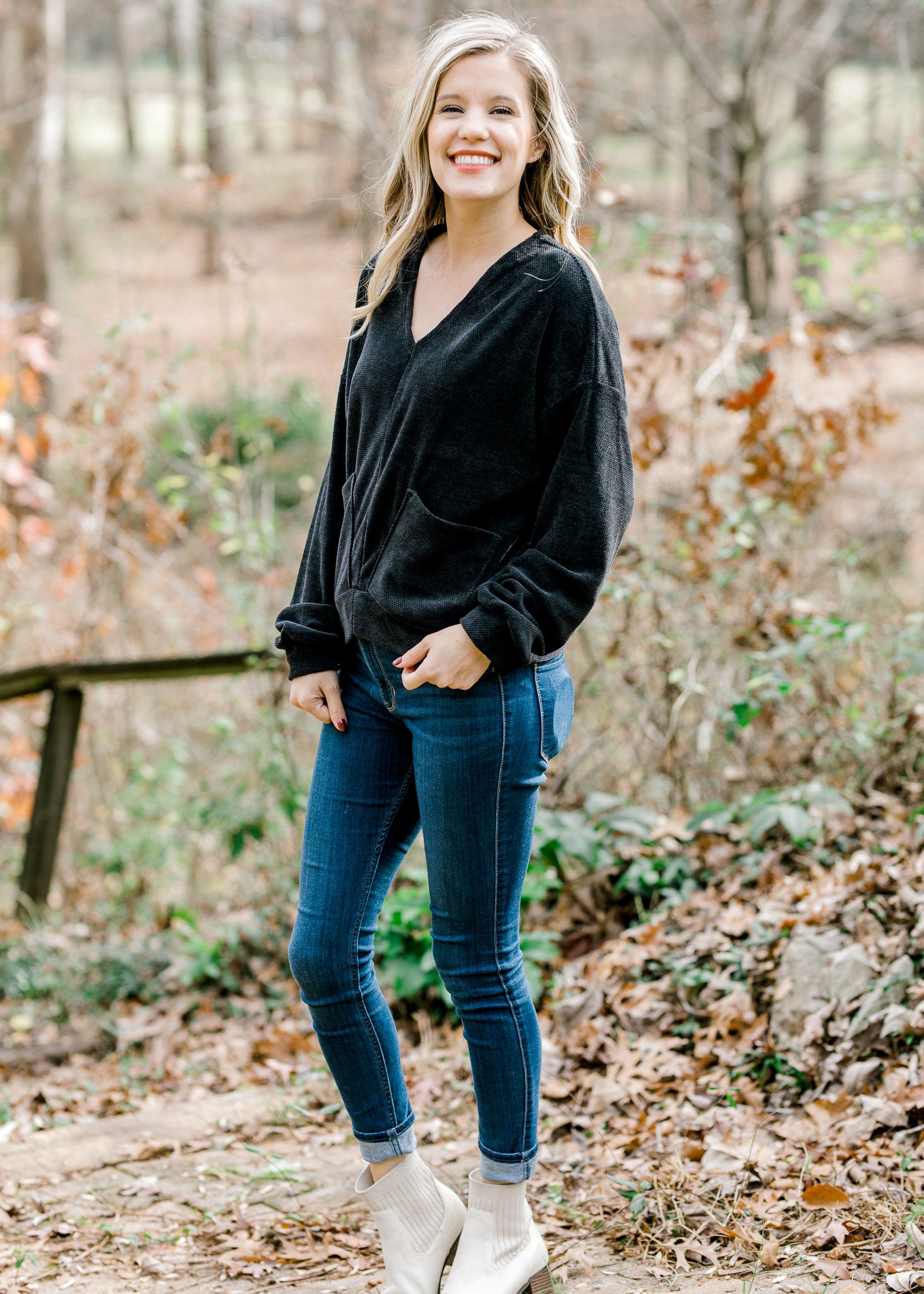Blonde model wearing black V-neck sweater with jeans. 