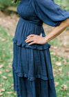 Model wearing navy dress with tiers.