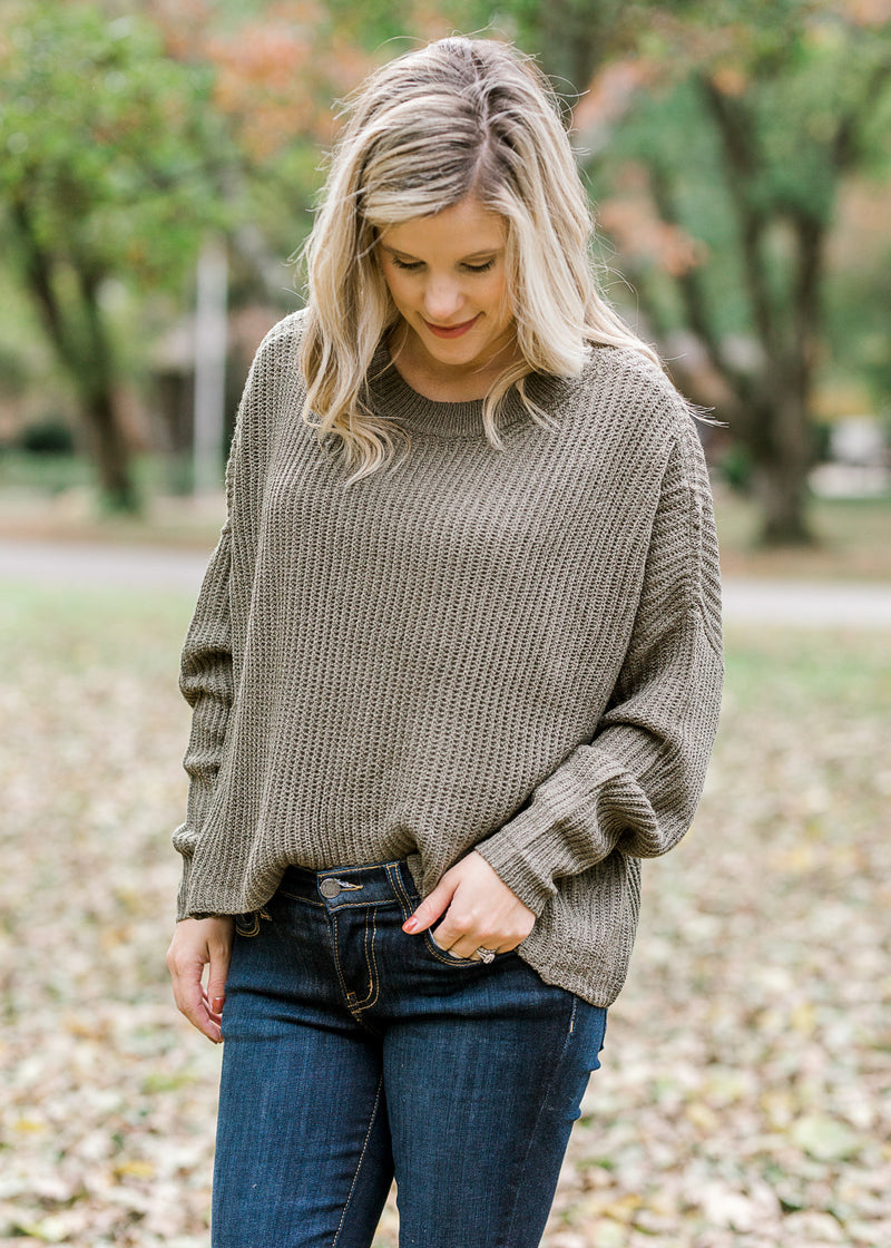 Blonde model wearing olive cable knit sweater.