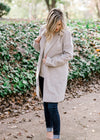 Blonde model wearing herringbone jacket with cream top and jeans.