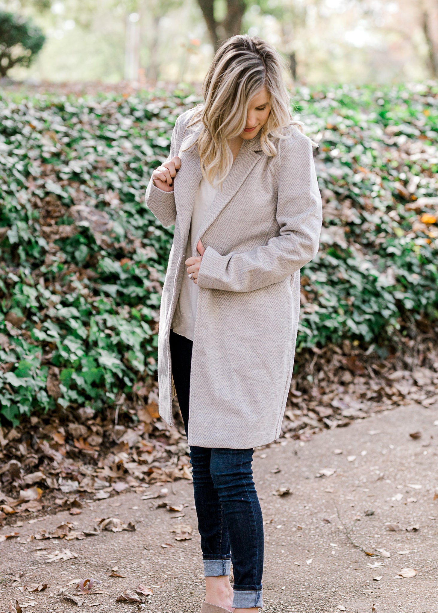 Blonde model wearing herringbone jacket with cream top and jeans.