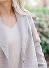 Close up view of blonde model is wearing herringbone coat. 