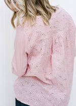 Back view of eyelets on Blonde model wearing a mauve top. 