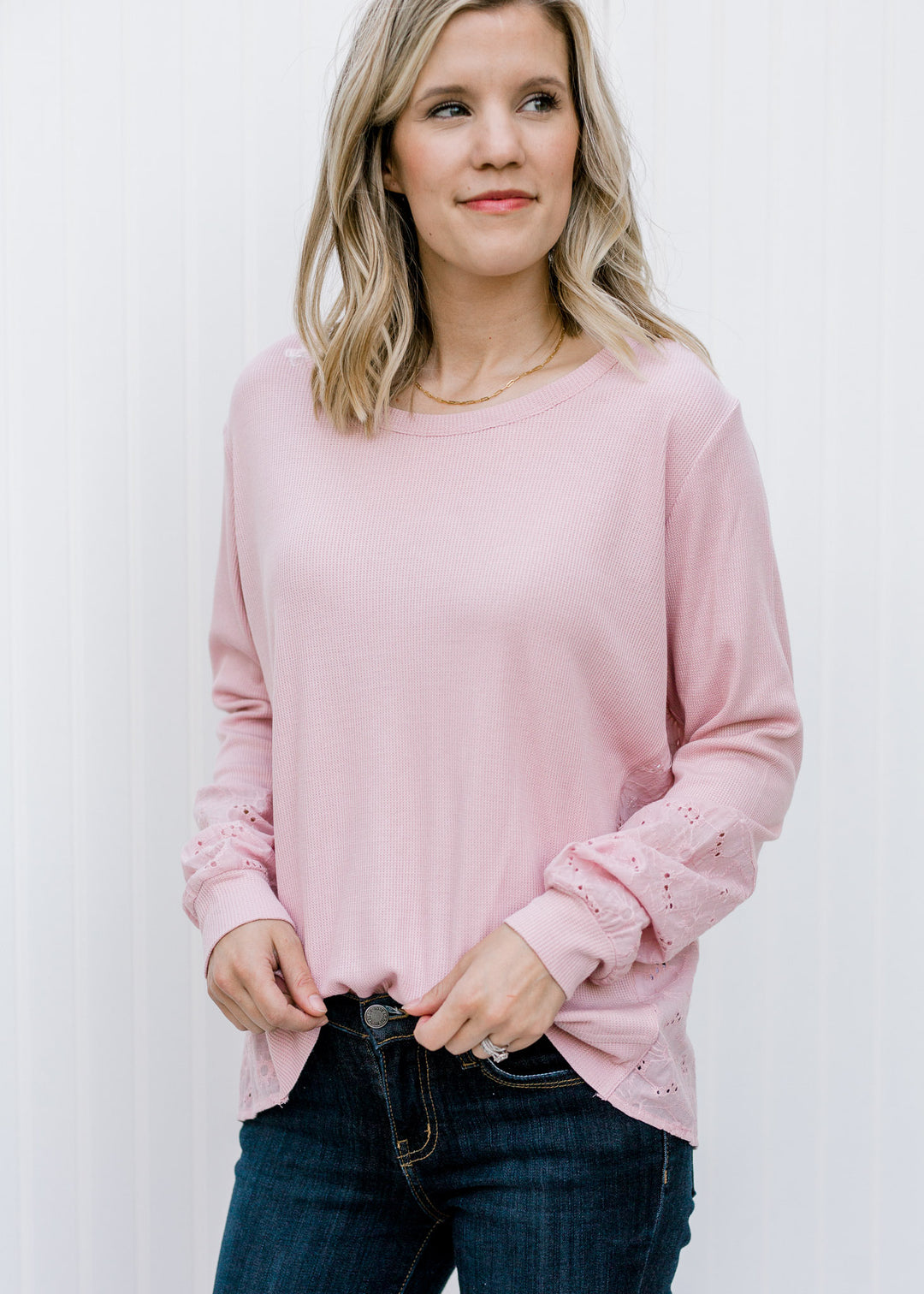 Blonde model wearing a mauve top with eyelet pattern. 