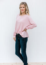 Blonde model wearing a mauve top with jeans. 