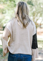 Back view of Blonde model wearing light gray, dark gray, taupe and camel color block sweater.