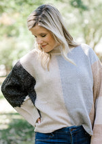 Blonde model wearing color block sweater with wide long sleeves.