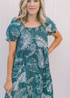 Close up view of bubble short sleeves and square neck on a turquoise midi dress with a fern pattern.