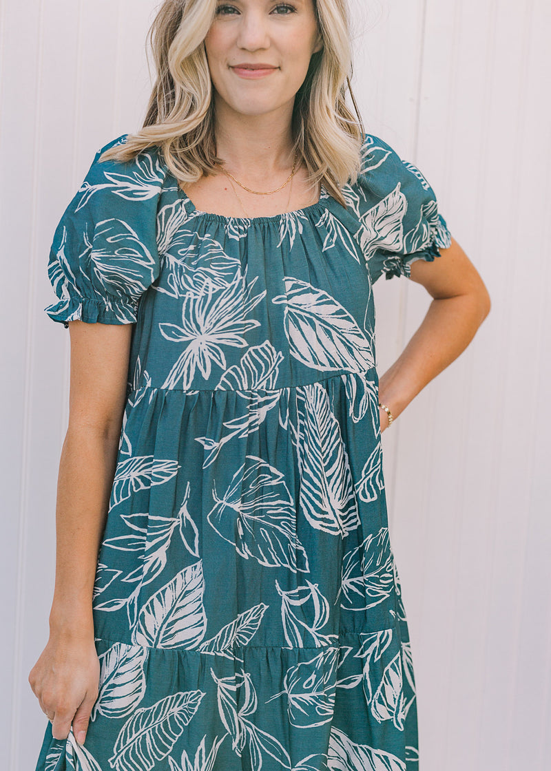 Close up view of bubble short sleeves and square neck on a turquoise midi dress with a fern pattern.