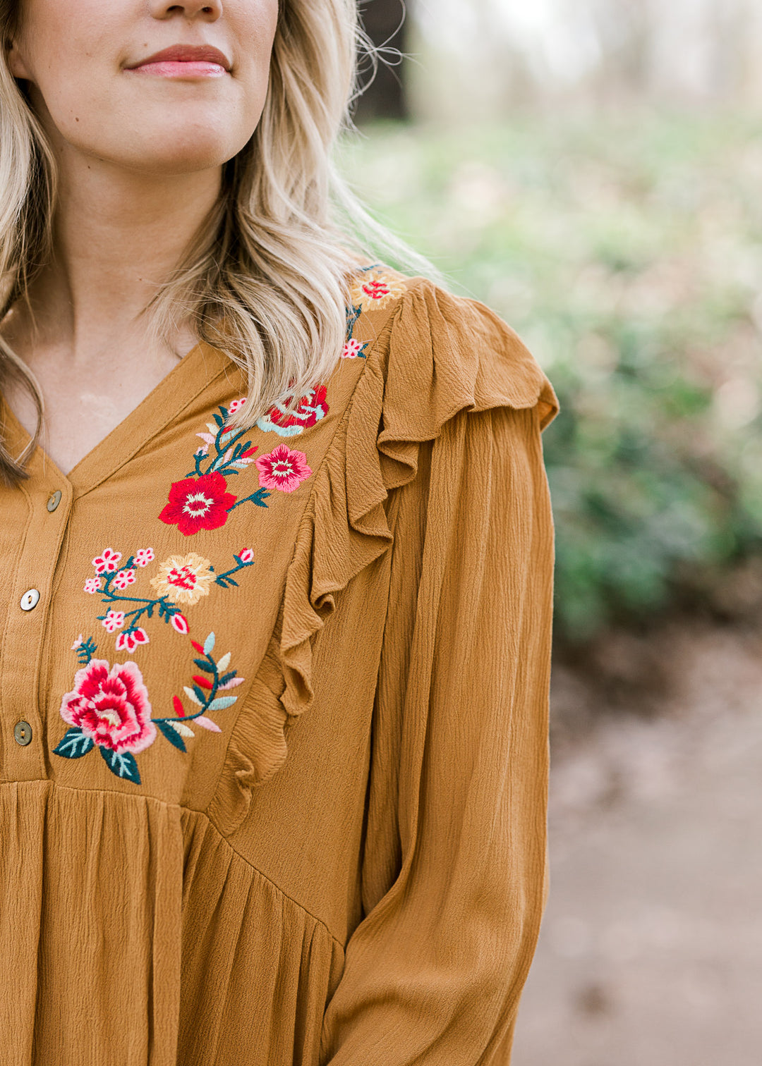 Close up view of embroidery on mustered top.