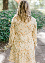Back view of Blonde model wearing cream corduroy dress with orange floral pattern.