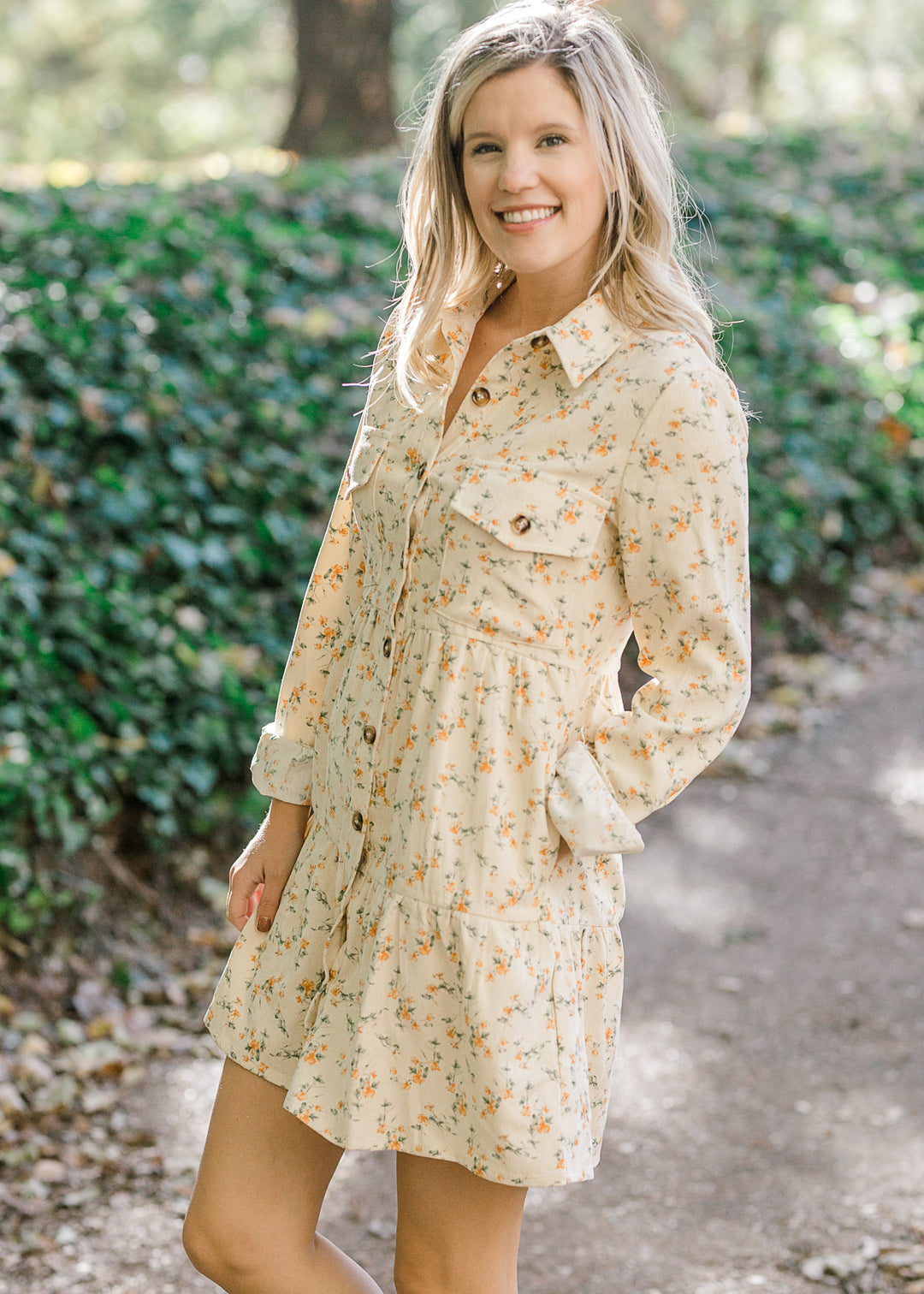 Blonde model wearing cream corduroy dress with orange floral pattern.