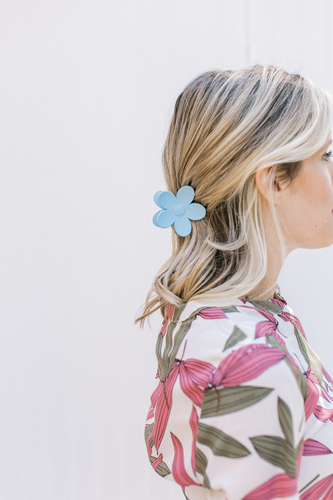 Model wearing a blue flower claw hair clip with a matte finish. 