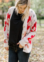 Blonde model wearing cream button up cardigan with floral design. 