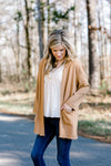 Blonde model wearing in cream blouse with camel colored lightweight in roadway jacket.