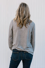 Back view of Blonde model wearing a gray top with a cowl neck.