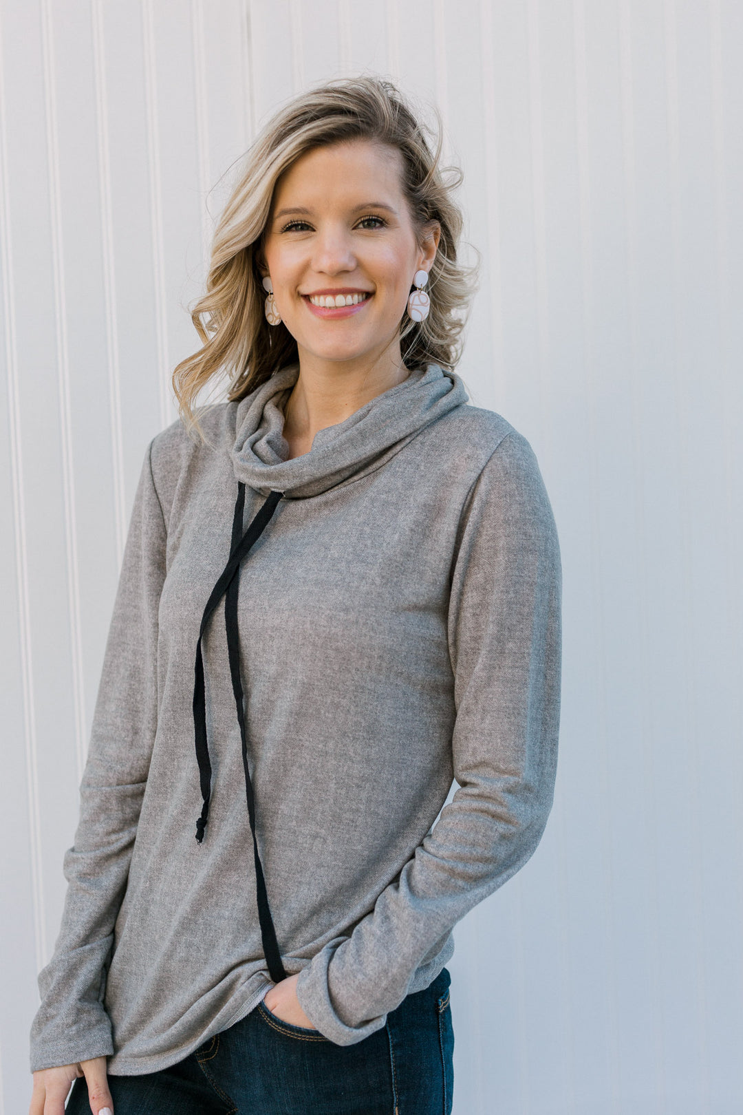 Blonde model wearing a gray top with a tie cowl neck.