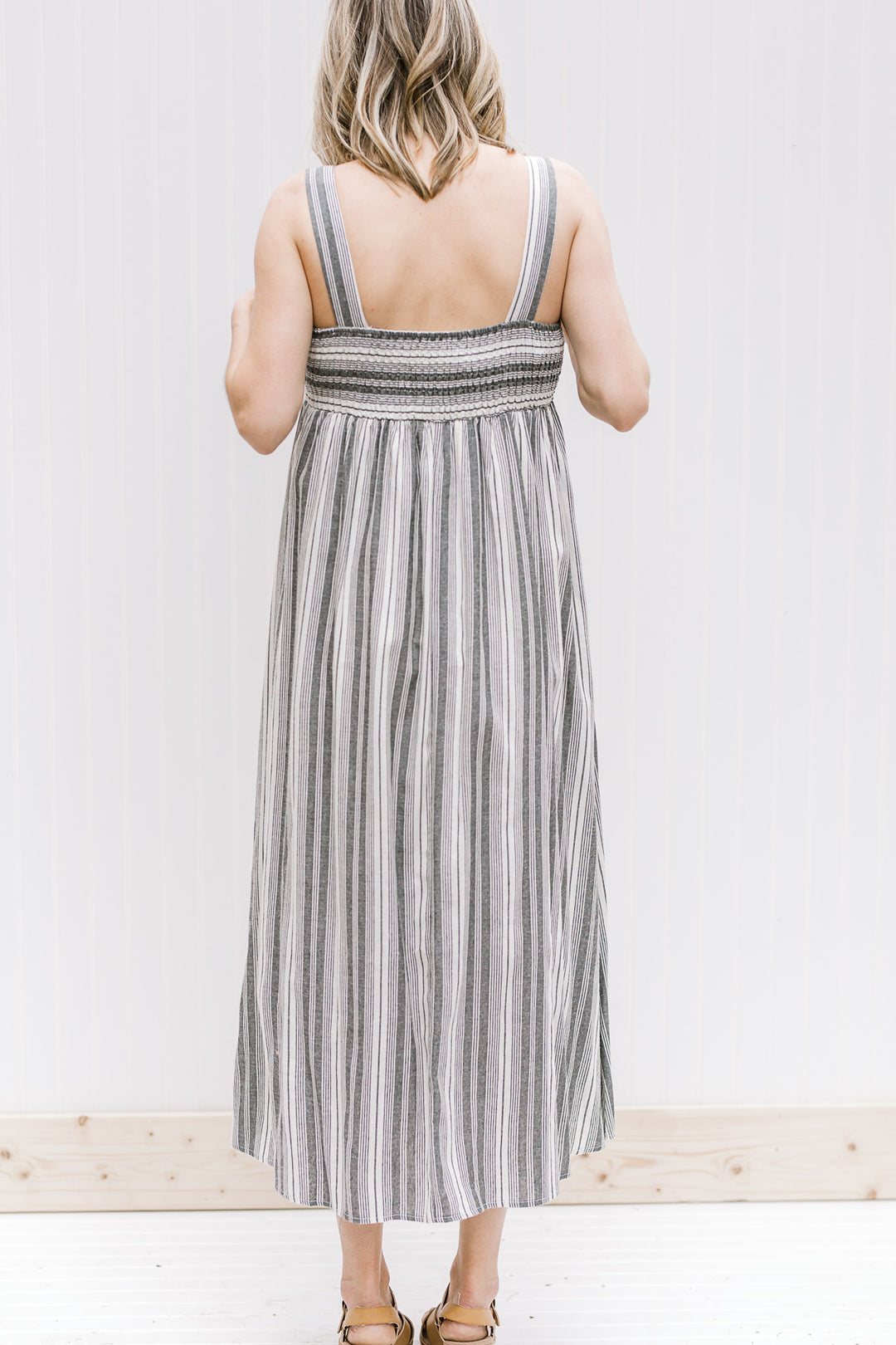 Back view of Model wearing black and white striped midi dress with 2 inch straps.