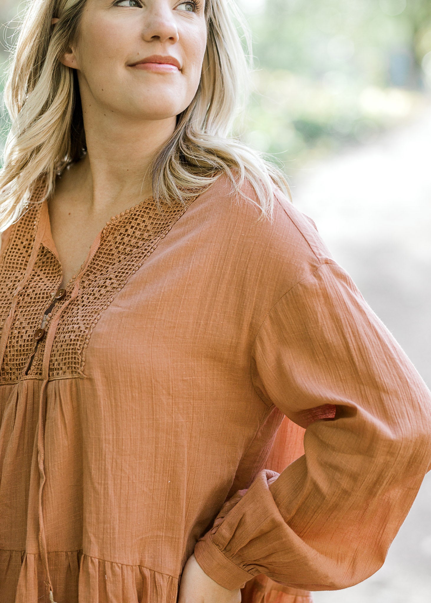 Close up detail view of textured fabric on ginger colored dress. 