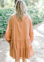 Back view of Blonde model wearing ginger colored, above the knee dress.