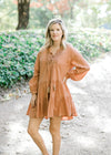 Blonde model wearing ginger colored, above the knee dress.