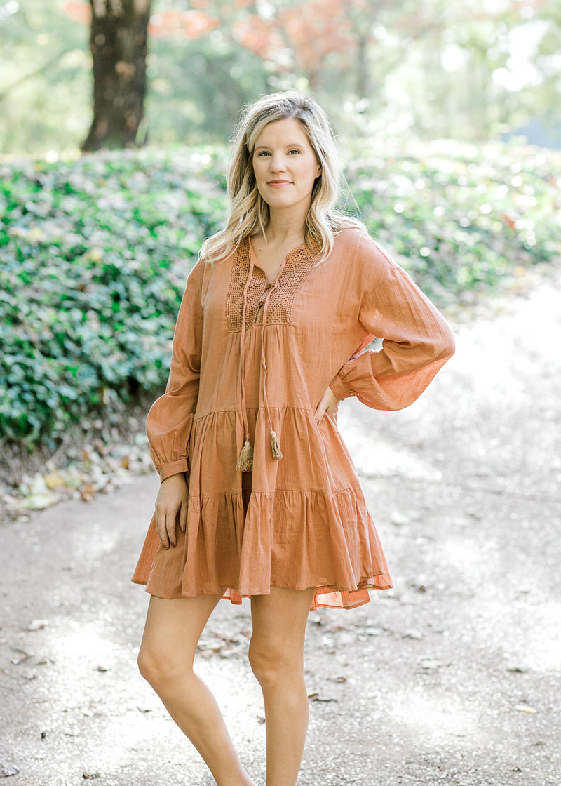 Blonde model wearing ginger colored, above the knee dress.