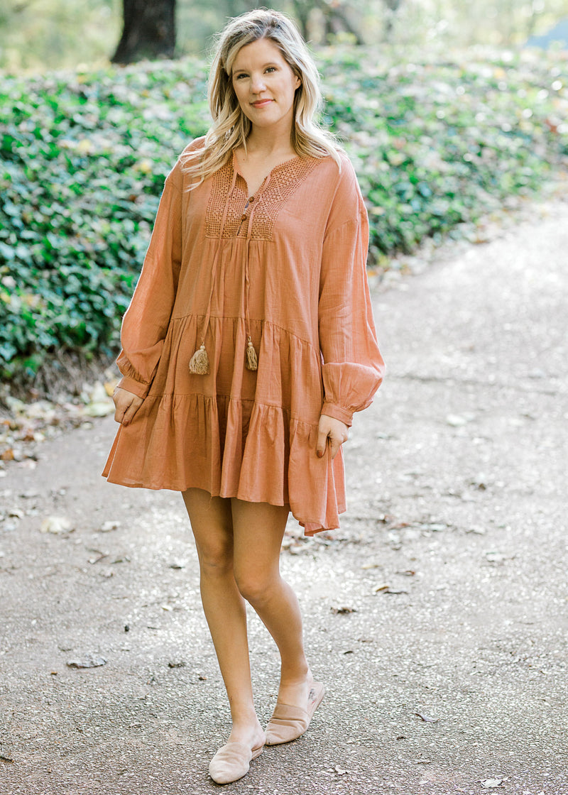 Blonde model wearing long sleeves, ginger colored, above the knee dress. 