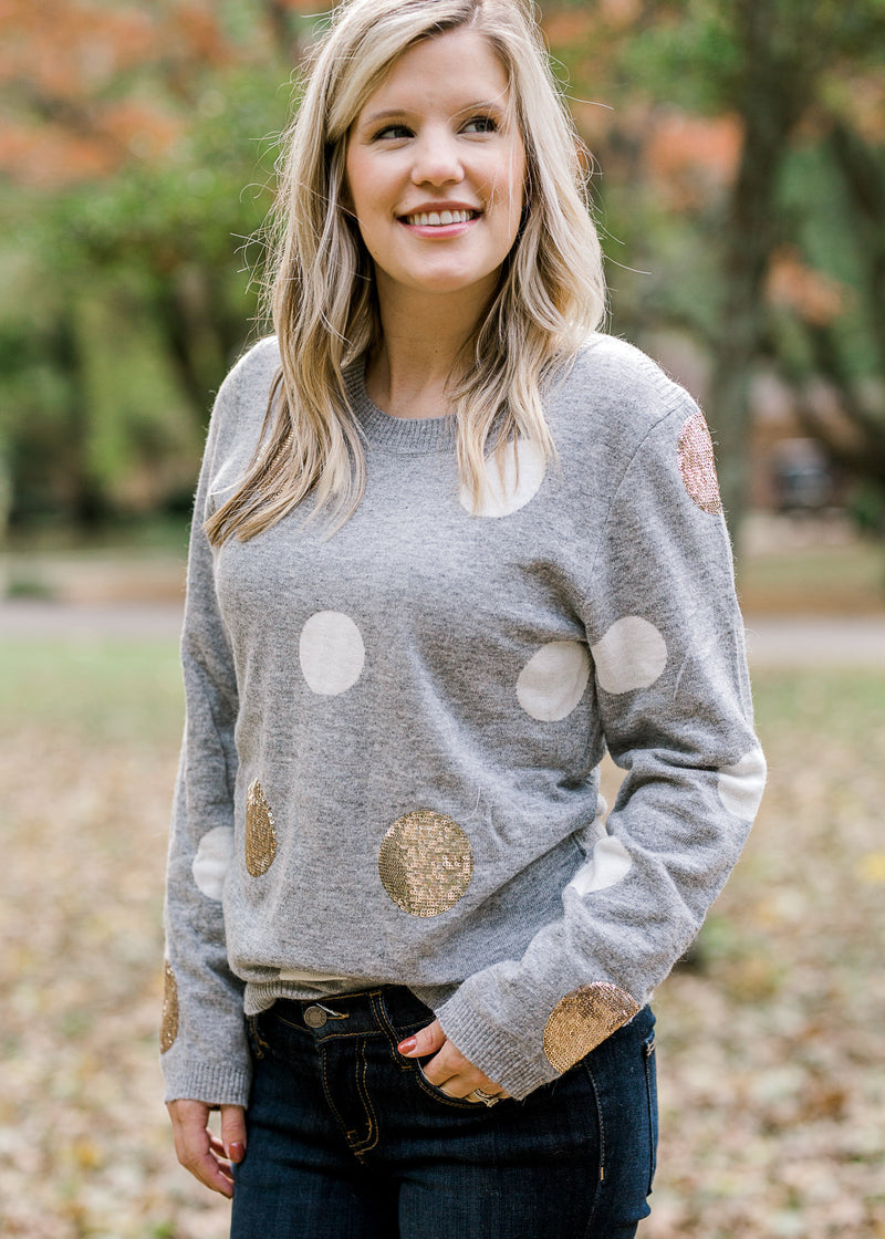 Blonde model wearing gray sweater with white and gold dots.