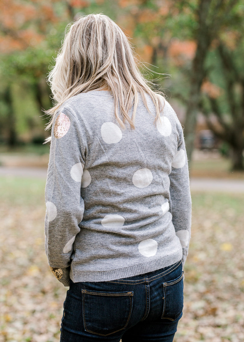 Back view of Blonde model wearing gray sweater with white and gold dots.