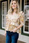 Blonde model wearing golden floral babydoll top with ruffles.