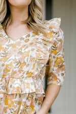 Close up view of ruffles on golden floral top.