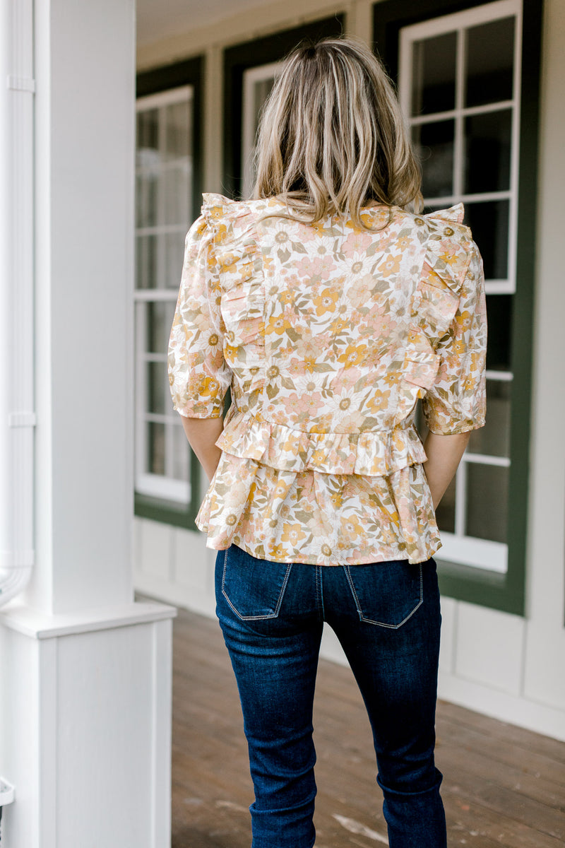 Back view of Blonde model wearing golden floral babydoll top with ruffles.