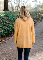 Back view of Blonde model wearing honey gold sweater. 