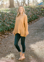 Blonde model wearing honey gold sweater with jeans and mules. 