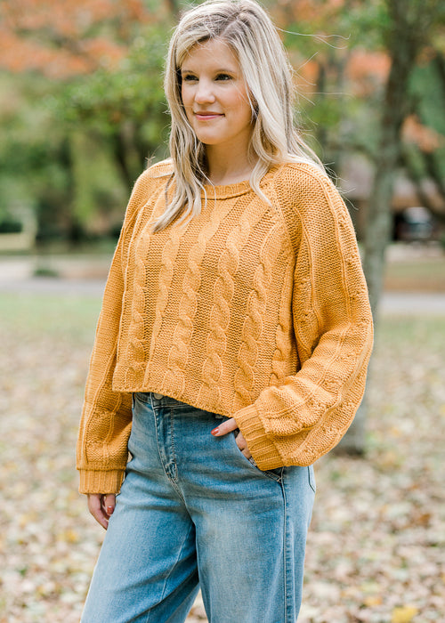 Blond model wearing gold cropped cable knit sweater.