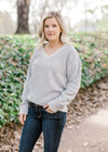 Blonde model wearing a gray v-neck sweater. 