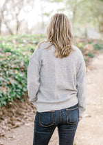 Back view of blonde model wearing gray sweater. 