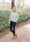 Blonde model wearing gray v-neck sweater with jeans and booties. 