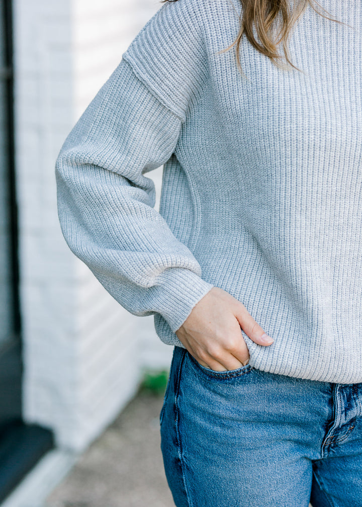 Close up view of brunette model wearing gray cable knit sweater.