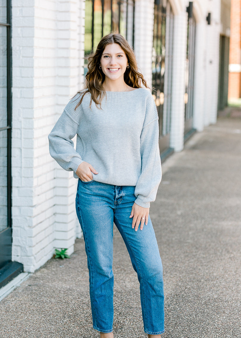 Brunette model with gray sweater with jeans.